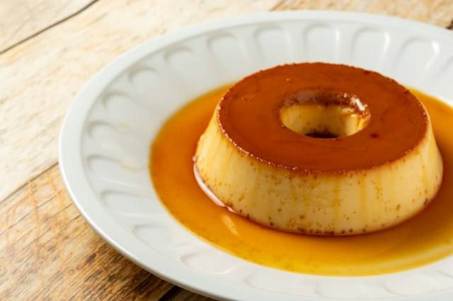 Chai flan se slaným karamelem Vyklopený flan přelitý karamelem na bílém talíři